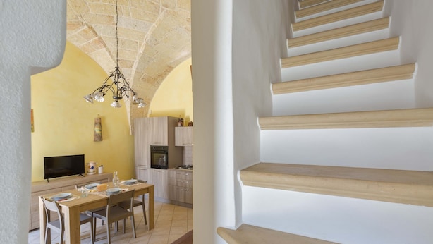 Une cuisine moderne avec un coin repas, un escalier et un plafond en pierre.