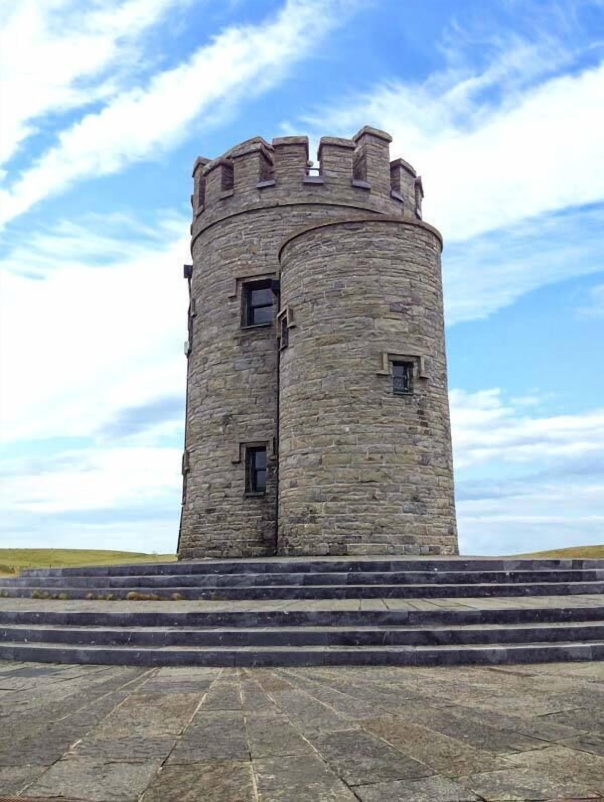 A stone tower with a circular base and a narrow top, featuring small windows and a flat roof.