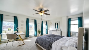 A bedroom with a bed, desk, chair, and a ceiling fan.