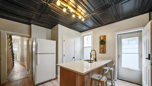 A modern kitchen with a central island, white appliances, and a black ceiling with recessed lighting.