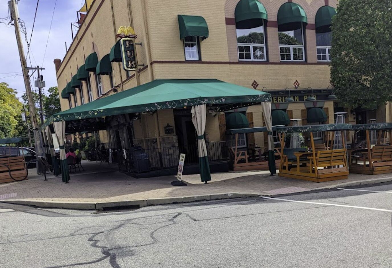 Un edificio con toldo verde, mesas al aire libre y un letrero que dice 'GERMAN RESTAURANT'.