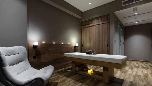 A massage therapy room with a wooden bench, a massage table, and wall-mounted lamps. - Standard Room In Jaddaf By E R (دبي)