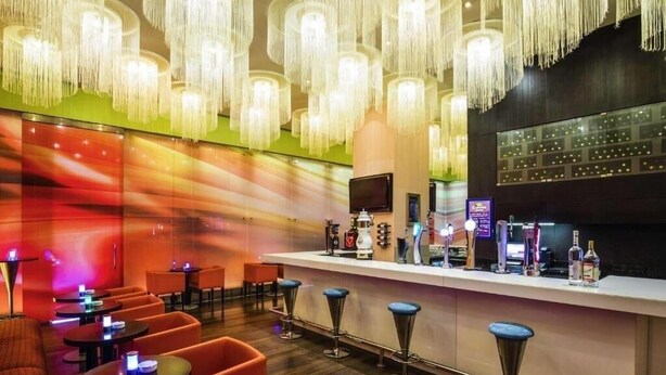 Zona de bar amb un disseny modern, amb llums penjants, una barra i diferents zones d'seure.