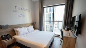 Une chambre d’hôtel avec un grand lit, un bureau, une télévision et une fenêtre donnant sur la ville.
