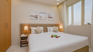 Een hotelkamer met een groot bed, twee bedlampen, een nachtkastje en drie foto's in lijsten aan de muur.