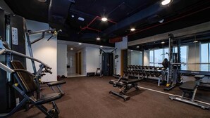 Een sportschool met diverse fitnessapparaten, waaronder krachtapparaten en gewichten.