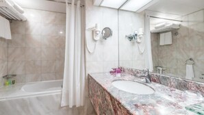 A modern bathroom with a marble sink, a bathtub, and a shower. - Standard Room Near Capital Park By E R (أبو ظبي)