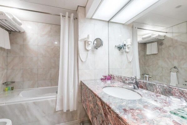 A modern bathroom with a marble sink, a bathtub, and a shower.