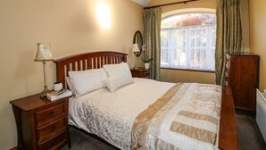 A bedroom with a bed, bedside table, lamp, dresser, and a window with curtains. - ROSEMOUNT COACH HOUSE, pet friendly in Enniscorthy, County Wexford (Marshalstown)