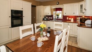 A kitchen with white cabinets, a wooden dining table, and a red tiled backsplash. - ROSEMOUNT COACH HOUSE, pet friendly in Enniscorthy, County Wexford (Marshalstown)