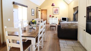 A cozy living room with a fireplace, a dining area with wooden furniture, and a television. - ROSEMOUNT COACH HOUSE, pet friendly in Enniscorthy, County Wexford (Marshalstown)