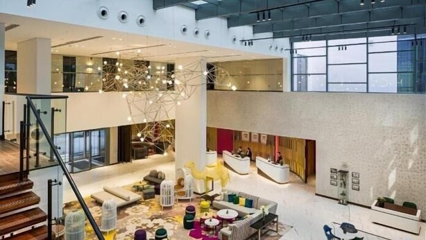 Un vestíbulo amplio con techo alto, mobiliario moderno y una zona de estar central.