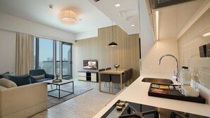 Een moderne hotelkamer met een zithoek, een eethoek en een kitchenette.
