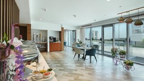 Een moderne hotelkamer met een eethoek, een keuken en grote ramen met uitzicht op de stad.