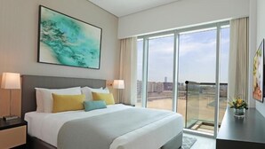 Hotelkamer met een groot bed, twee bedlampen, stadszicht door raam-tot-vloer ramen en een modern abstract schilderij aan de muur.