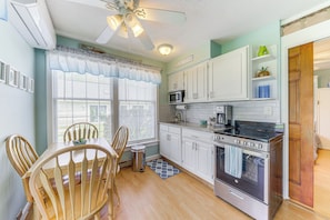 A kitchen with white cabinets, a microwave, a stove, and a ceiling fan. - 2 Mi to Drakes Island Beach: Condo w/ Porch! (Wells)