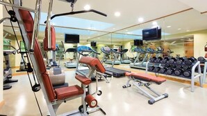 Une salle de sport équipée de machines de cardio, de matériel de musculation et dotée d’un mur entièrement recouvert de miroirs.