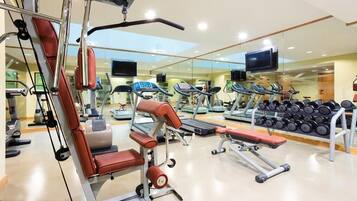 Uma academia com aparelhos de cardio, equipamentos de musculação e um painel de espelhos.