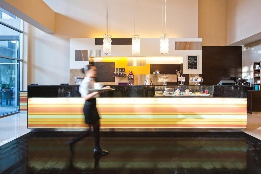 Een moderne hotel lobby met een centraal gelegen balie, grote ramen en hangende吊り下げ式灯具.
