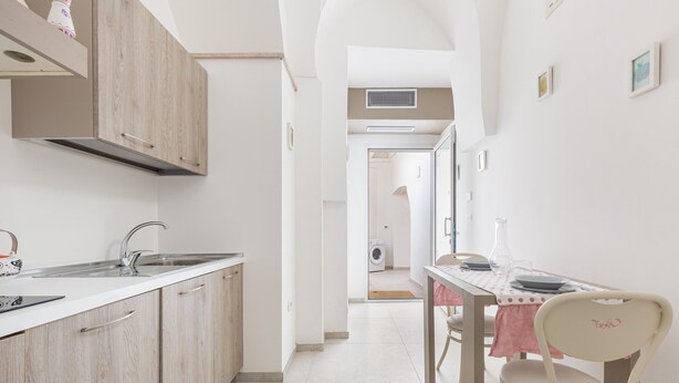 Eine moderne Küche mit Holzausstattung, einem Spülbecken und einem Essbereich mit Tisch und Stühlen.