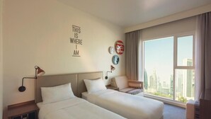 A hotel room with two beds, a large window with a city view, a wall-mounted lamp, and a decorative sign. - King Room Near Civil Defance Downtown by E R (Dubai)