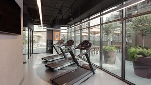A modern gym with treadmills and large windows overlooking an outdoor area. - King Room Near Civil Defance Downtown by E R (Dubai)