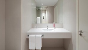 A modern bathroom with a white sink, mirror, and towel rack. - King Room Near Civil Defance Downtown by E R (Dubai)