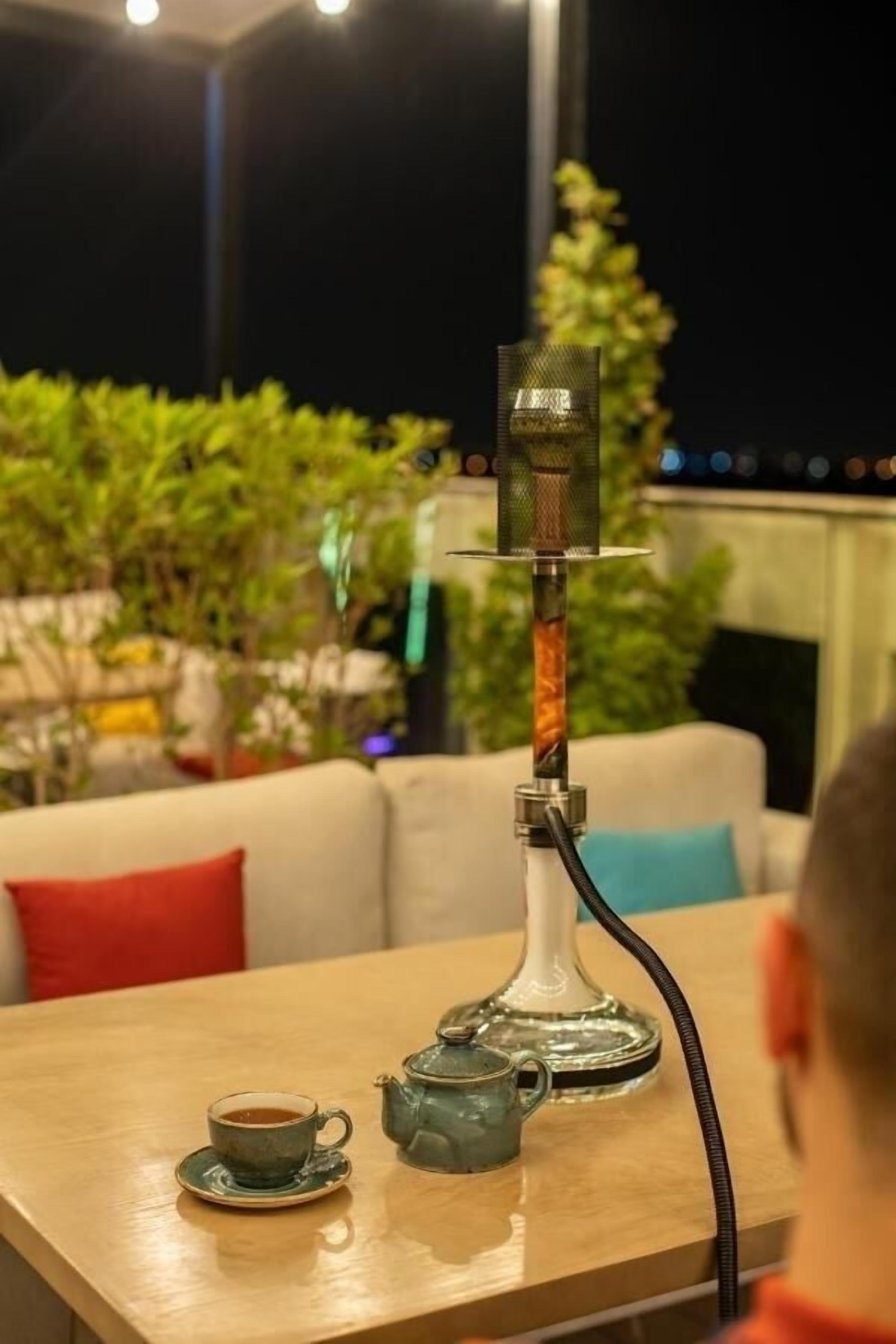 Un narghilè su un tavolo con una tazza di tè e un teiera.
