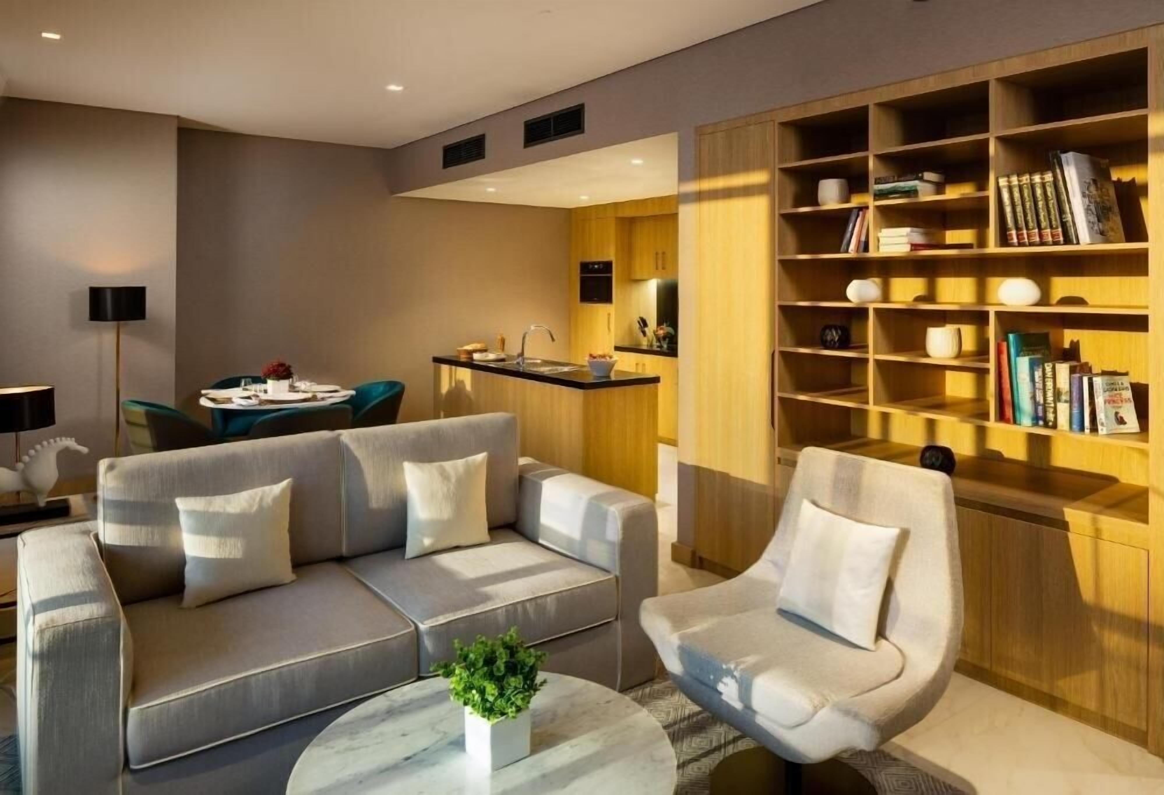 Een moderne woonkamer met een bank, fauteuil, salontafel en een boekenplank.