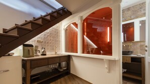 Una cocina compacta con encimera de madera, horno empotrado y ventana con marco rojo.