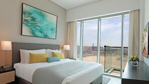 A hotel room with a large bed, two bedside tables, a nightstand, a view of the city through large windows, and a painting on the wall. - One Bedroom Apartment In Science Park By E R (Dubai)