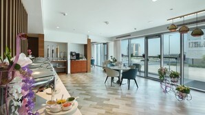 A modern hotel room with a dining area, a kitchen, and large windows offering a city view. - One Bedroom Apartment In Science Park By E R (Dubai)