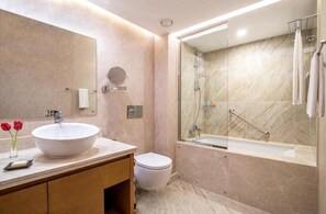 Un baño moderno con un lavamanos grande blanco, un inodoro y una zona de ducha con mampara de cristal.