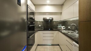 Una cucina moderna con forno integrato, microonde, piano cottura a gas, lavello e cappa aspirante in acciaio inossidabile.