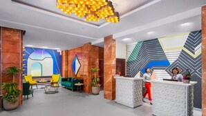 Un hall d’entrée moderne avec un comptoir d’accueil, un espace détente agrémenté de plantes et des murs décoratifs.