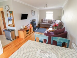 Relax in this stylish living room with a flat-screen TV, comfortable sofa, and dining area.