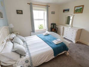 Cozy retreat with a neatly made bed, dresser, and comfortable chair.