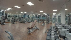 Une salle de sport équipée de divers appareils d’exercice, notamment des tapis de course, des vélos d’appartement et des poids libres.