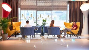 A modern lobby with yellow armchairs, a blue sofa, and a large window with curtains. - Two Bedroom Apartment Near Dic Metro (Dubai)