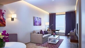 Ein modernes Hotelzimmer mit einer Couch, einem Sessel und einem Esstisch.