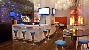 Eine Bar mit modernem Design, inklusive einer Theke, Barhocker und hängenden Leuchten.