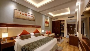 A hotel room with a large bed, a desk, a chair, a TV, and a bathroom visible through an open door. - Deluxe Room Near Mashreq Metro Station By E R (Dubai)