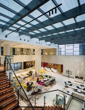 Experience the hotel's inviting lobby with a high ceiling, comfortable seating areas, and a staircase leading to an upper level.