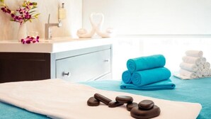 A spa area with a massage table, rolled towels, and massage stones. - Standard Room Near Rabdan Majlis By E R (Area)
