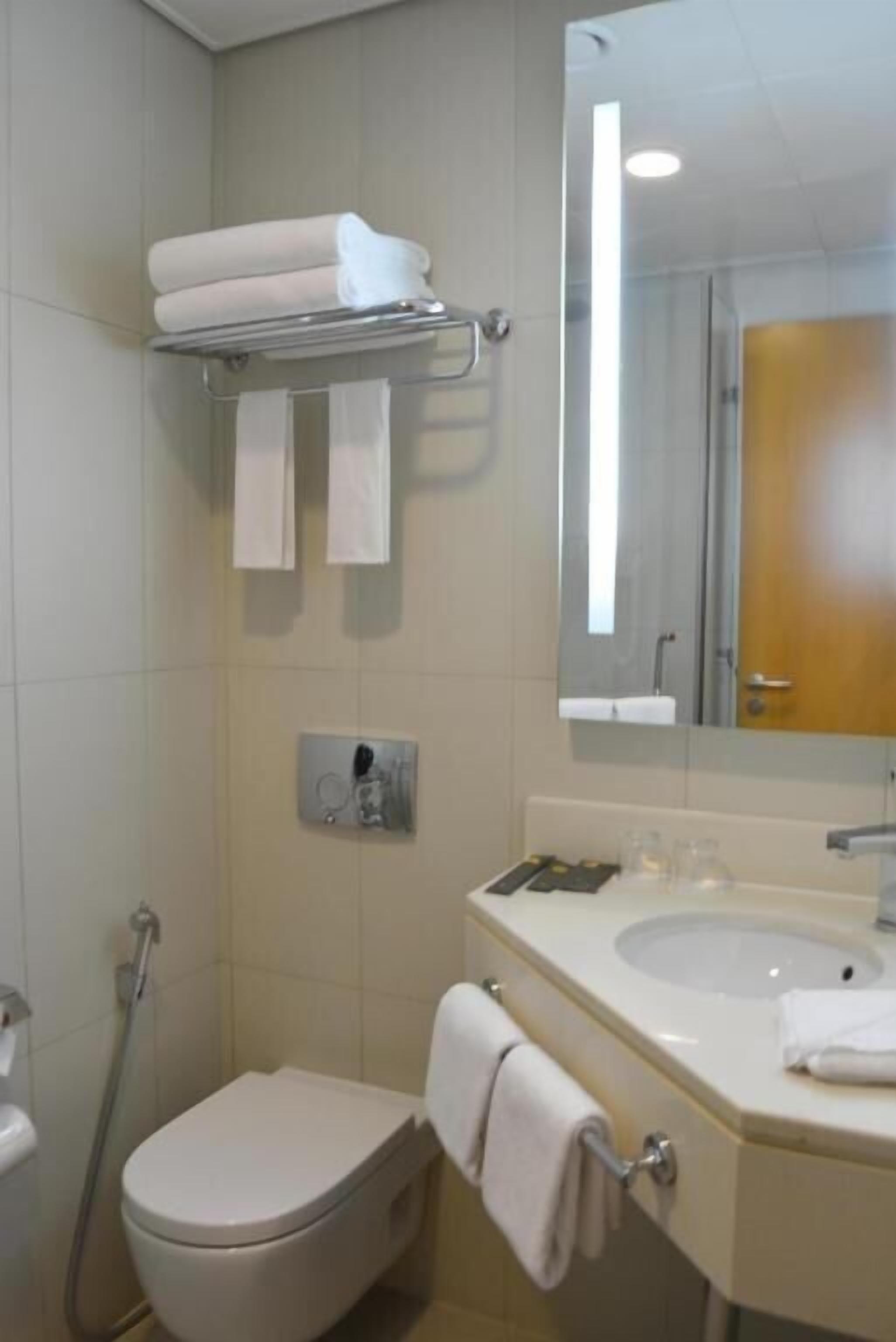 Une salle de bain équipée de toilettes, d’un lavabo et d’un porte-serviettes avec des serviettes pliées.