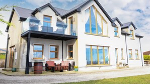 A modern two-story house with large windows, a balcony, and a well-maintained lawn. - MILLERS LANE HOUSE, pet friendly in Muff, County Donegal (Muff)