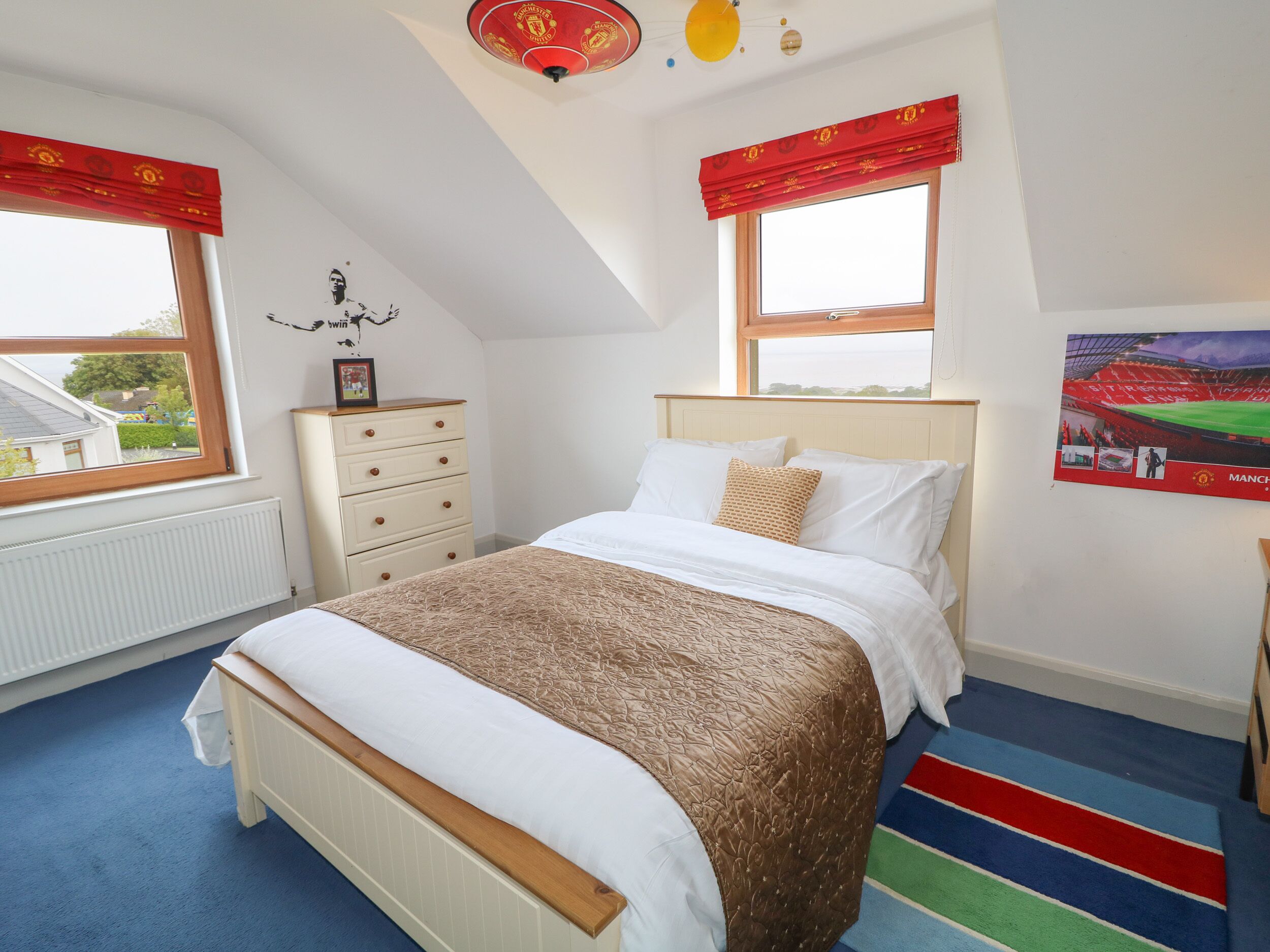 Une chambre à coucher comprenant un lit, une commode, un radiateur et une fenêtre donnant sur l’extérieur.