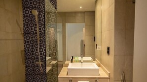 A modern bathroom with a large mirror, a sink, and a shower.