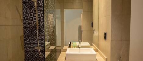 A modern bathroom with a large mirror, a sink, and a shower.
