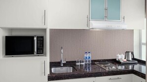 A modern kitchen with white cabinets, a black microwave, a stainless steel sink, and a coffee maker. - Deluxe Room Near Burj Khalifa Metro By E R (Dubai)